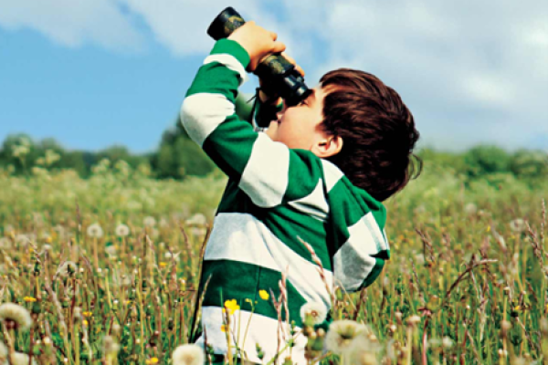 A child looking through binoculars.